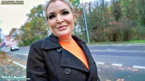 Blonde bombshell in black leather coat smiles seductively on public street roadside