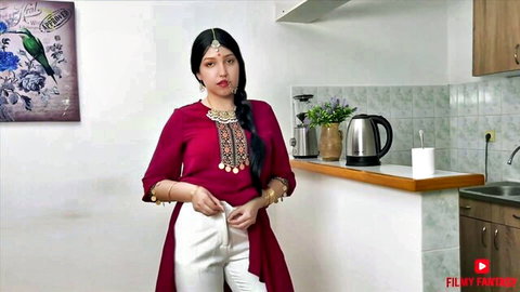Sexy Indian woman in red embroidered kurti and white salwar posing teasingly in kitchen
