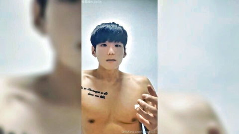 Sexy shirtless Asian guy flexing muscular bare chest with au revoir tattoo