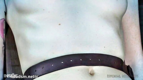 Tattooed figure in belt harness for BDSM punishment scene