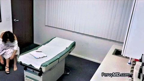 Busty Latina patient in open medical gown sitting distressed on exam room floor