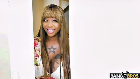 Smiling ebony woman with huge cleavage, star tattoo in floral dress