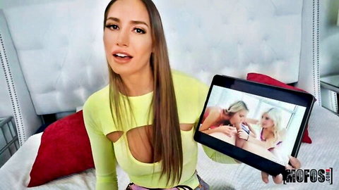 Desiree Dulce in revealing yellow top holding POV threesome sex scene tablet