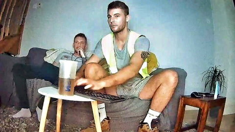 Two fit British lads in casual clothes chatting on laptop in amateur gay setup