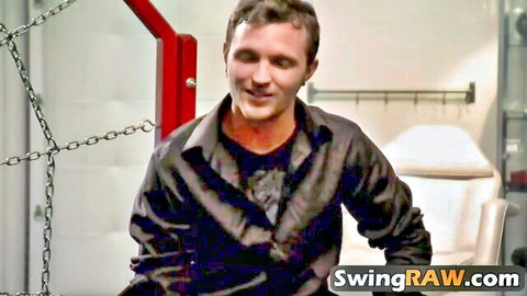 Smiling man in leather shirt in bondage setup, swinger reality show