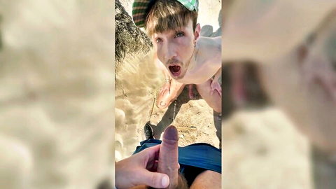 Blonde hunk in cap pulls down blue shorts to grip his thick erect cock on beach