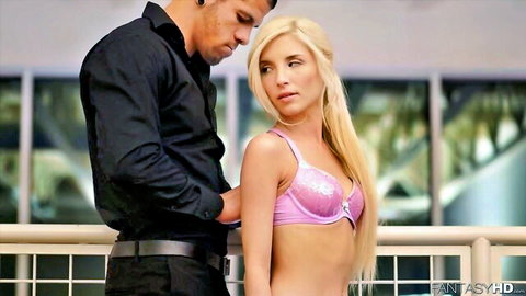 Petite blonde babe in shiny pink bra looks back seductively as dark stud grabs her arm on balcony