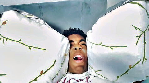 Young black man in ecstasy, pillows framing face in Aubrey Black college cheating scene