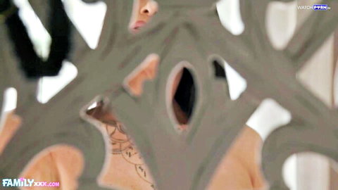 Tattooed muscular hunk presses close to metal grate as seductive fair-skinned brunette peeks through with parted lips