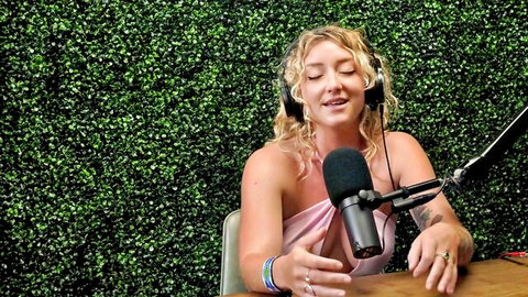 Susie Stellar blonde bombshell in pink top at mic, smiling with headphones
