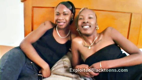 Two smiling black teen girlfriends lounging in casual tops, teasing threesome preview