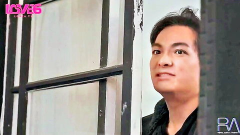 Asian man smiling seductively through metal bars in Love65 studio scene