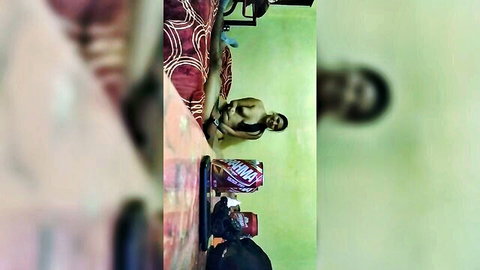Blurry naked dark-skinned man sitting on red bed with hard cock and balls exposed