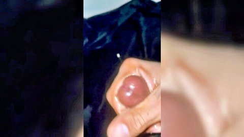Hand gripping and squeezing shiny swollen pink cockhead up close