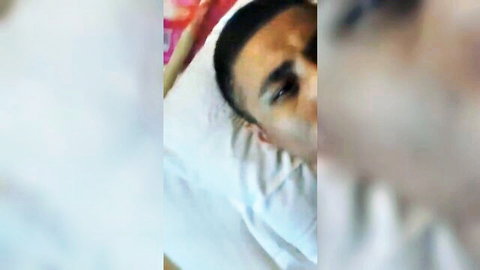 Close-up of Asian man's pained face on pillow in slapping slave scene