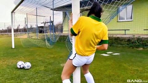 Tanned babe in Brazilian soccer jersey bends over, teasing round ass in short shorts