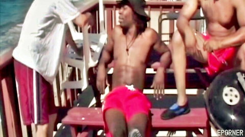 Muscular ebony men in red swim shorts lounging on boat deck