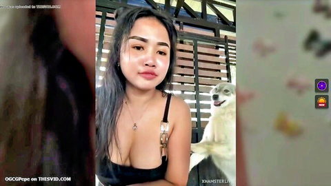 Asian woman in low-cut black top showing cleavage, walking with dog outdoors
