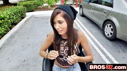 Brunette wheelchair girl in tank top and jeans poses in parking lot