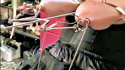 Bound woman in black corset with nipple clamps and chains in BDSM pose