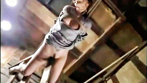 Bound Asian woman exposed in torn shirt during prison interrogation