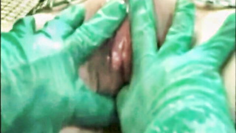 Gloved hands in green latex spreading shaved pussy lips wide open exposing wet pink vagina
