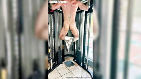 Naked muscular stud hangs upside down on gym rack exposing tight ass and balls