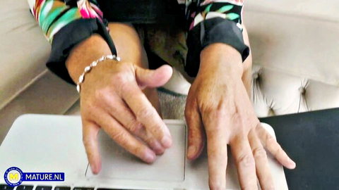Closeup of wrinkled granny hands with bracelets typing on laptop keyboard