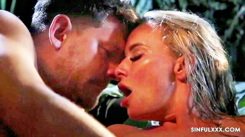 Passionate blonde kissed by muscular man in steamy jungle embrace
