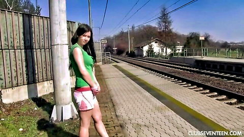 Asian teen in green top and mini skirt poses outdoors by train tracks