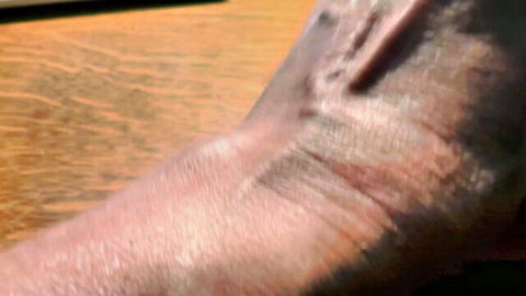 Close-up of tanned woman's forearm and wrist on wooden surface, amateur style