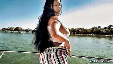 Selena Adams posing seductively on boat deck in white top and striped pants