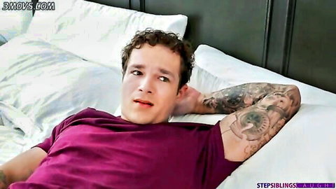 Tattooed young man with curly hair lounging on bed in purple shirt, stepsis theme