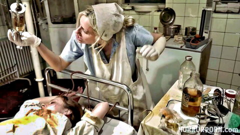 Blonde nurse in uniform giving IV to restrained redhead patient in medical fetish scene