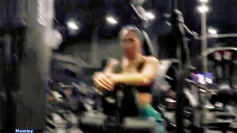 Muscular fit baddie in tight teal sports bra and shorts sitting on gym machine teasing