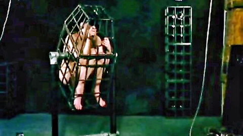 Naked slim woman bound in metal cage intense BDSM restraint scene