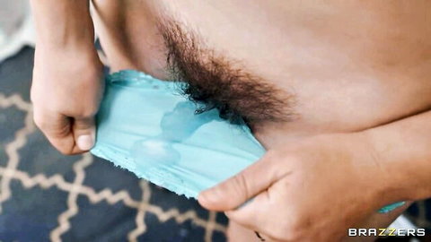 Woman pulls aside wet blue panties revealing bushy pubic hair closeup