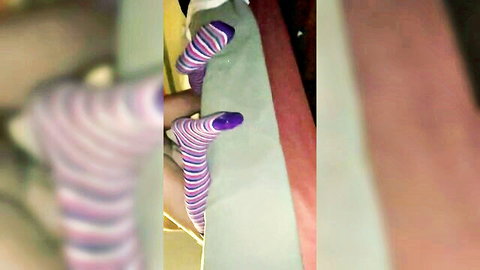 Blurry closeup of woman's legs in purple striped socks on hotel bed