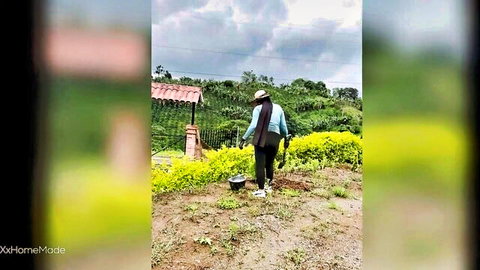 Colombian farm woman in blue shirt and hat walking through rural fields with yellow flowers