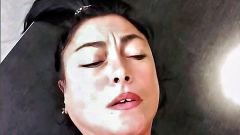 Close-up of brunette mature woman's ecstatic face with parted lips moaning in pleasure