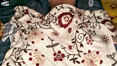 Amateur couple cuddling intimately under pink floral embroidered blanket hiding creampie pussy and cock