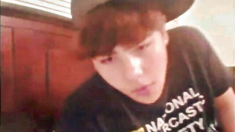 Amateur Asian guy with reddish hair in black shirt and hat on webcam