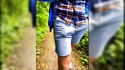 Muscular guy teasing huge bulge in tight blue shorts on forest path