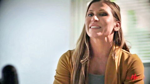 Smiling blonde MILF in open rust cardigan showing gray top cleavage