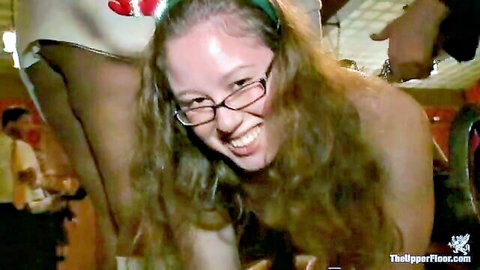 Topless smiling Asian submissive with glasses exposes perky tits at BDSM party