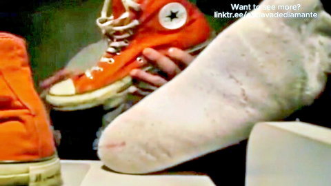 Youngster's smelly white socks and feet in orange Converse sneakers
