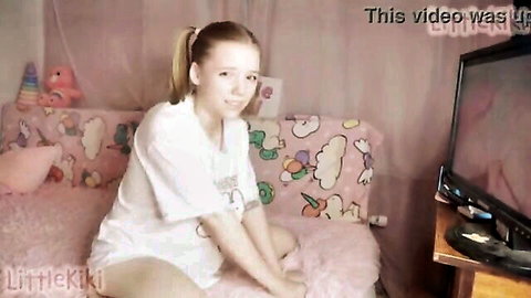 Blonde teen girl in white t-shirt sitting on pink bed, taboo stepdaughter theme