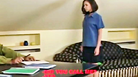 Submissive woman in blue polo and short black skirt stands obediently before military man in uniform at desk