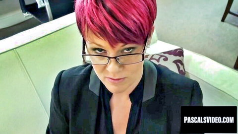 Stern pink-haired MILF in glasses and black suit stares dominantly at camera