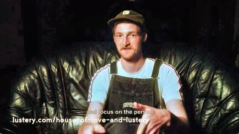 Bearded man in denim overalls and cap lounging on leather couch in lustery house of love orgy series